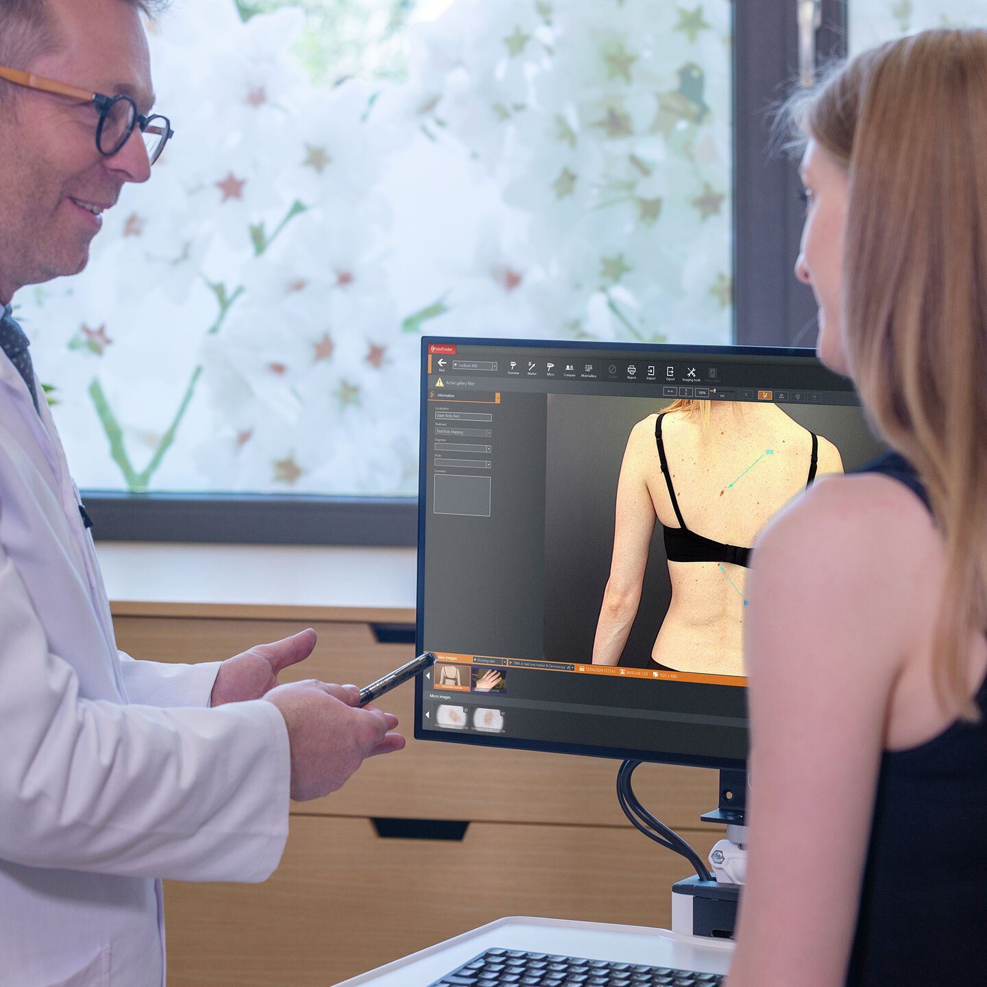 Arzt erklärt einer Patientin die digitale Ganzkörperaufnahme auf dem Bildschirm.