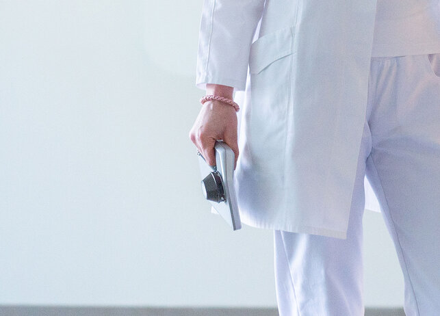 Ärztin oder Arzt in weißem Kittel mit skeen Gerät in der Hand